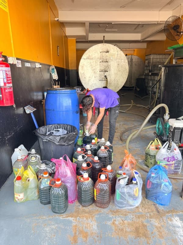 A car boot full of used cooking oil jerry cans and bottles by the roadside