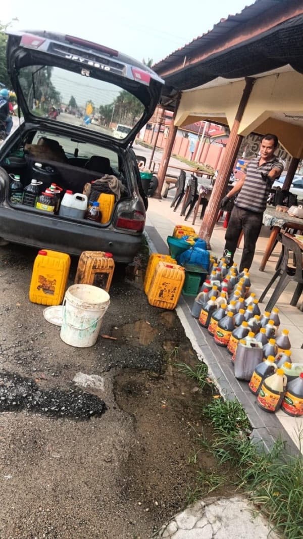 An MSR staff member opening bottles of used cooking oil delivered by a customer