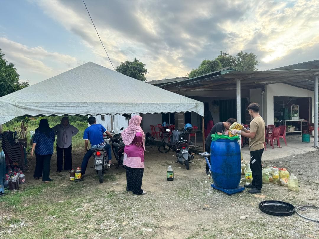 Customers and MSR staff weighing used cooking oil under a tent at the collection site