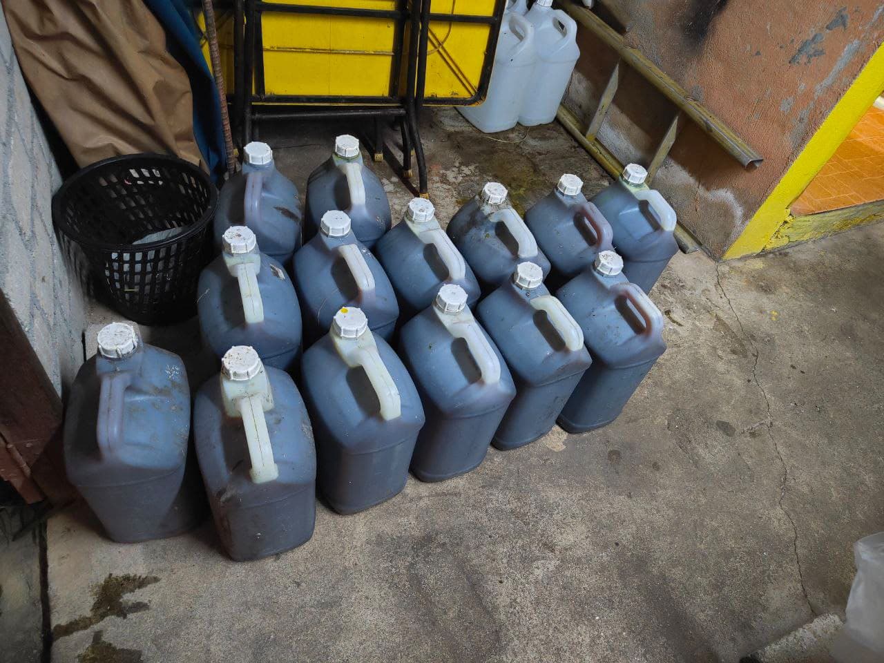 Used cooking oil jerry cans lined up in a row in a corner of the warehouse