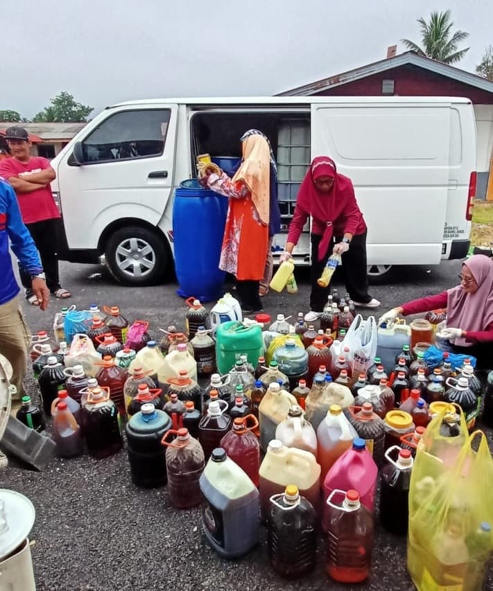 A white van at a collection site with many bottles and drums of used cooking oil