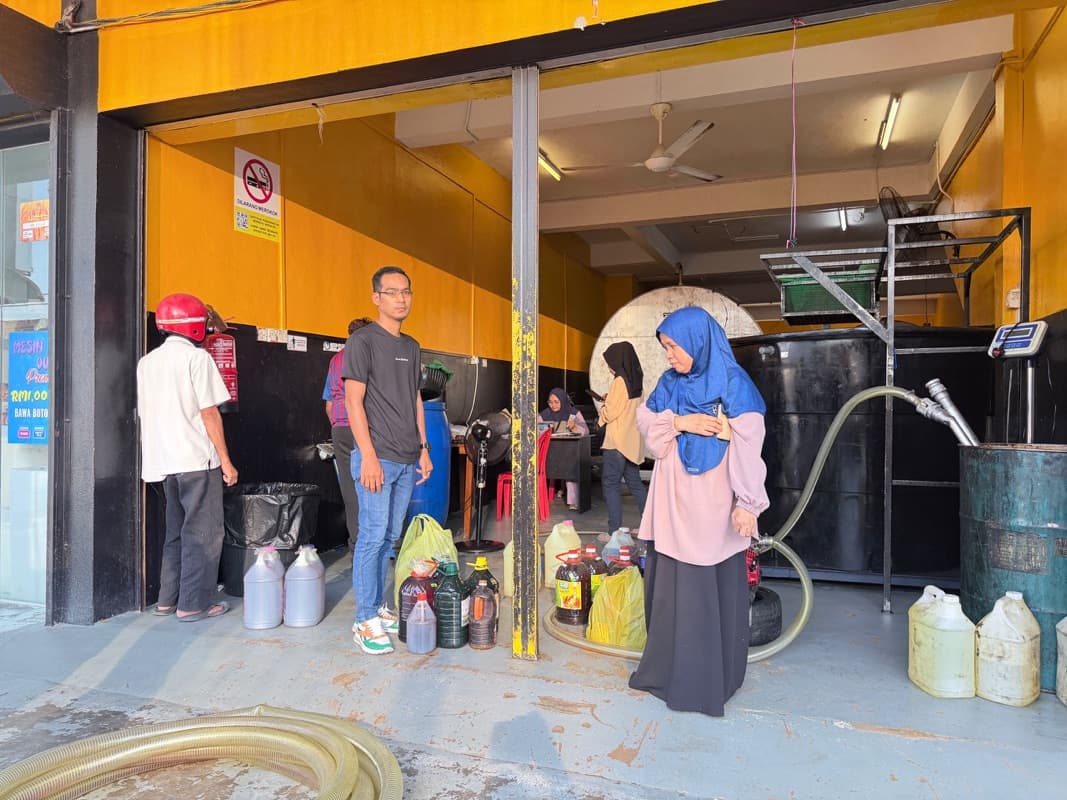Customers bringing bottles of used cooking oil to the MSR warehouse to be weighed